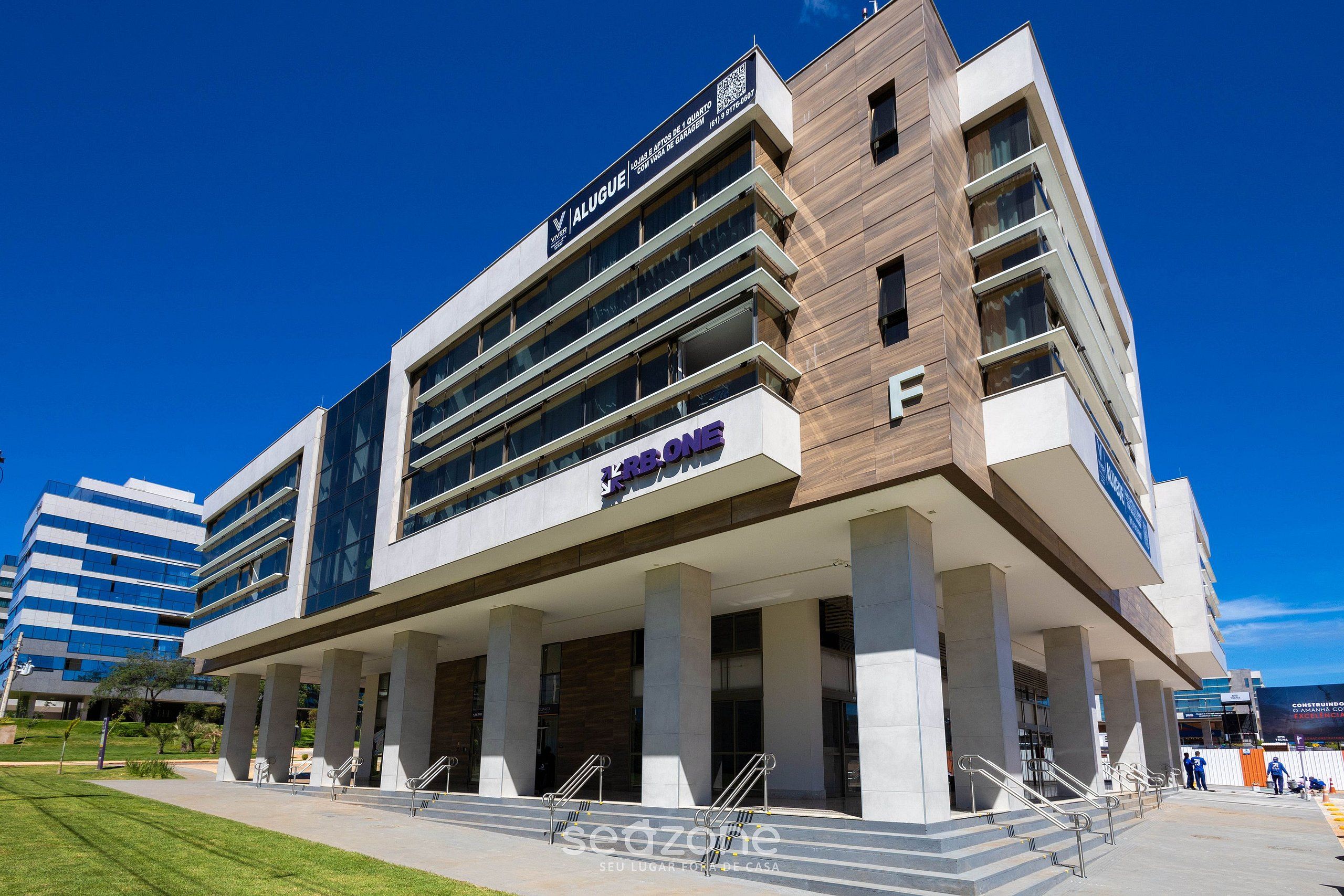 A modern building with a prominent 'Alugue' sign, multiple floors, and a 'KBBONE' logo.
