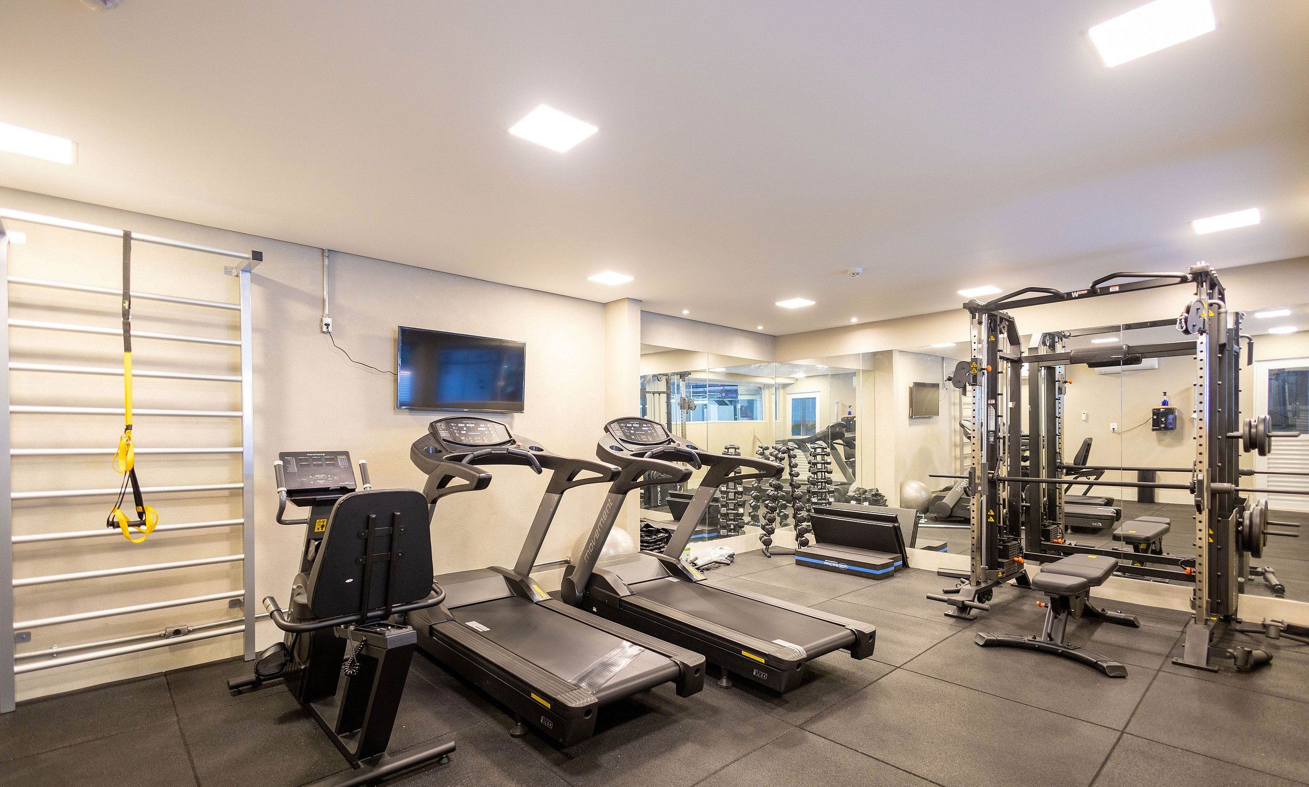 A gym with treadmills, weight machines, and a mirror wall.