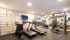 Una palestra con tapis roulant, macchinari per pesi e una parete con specchi.