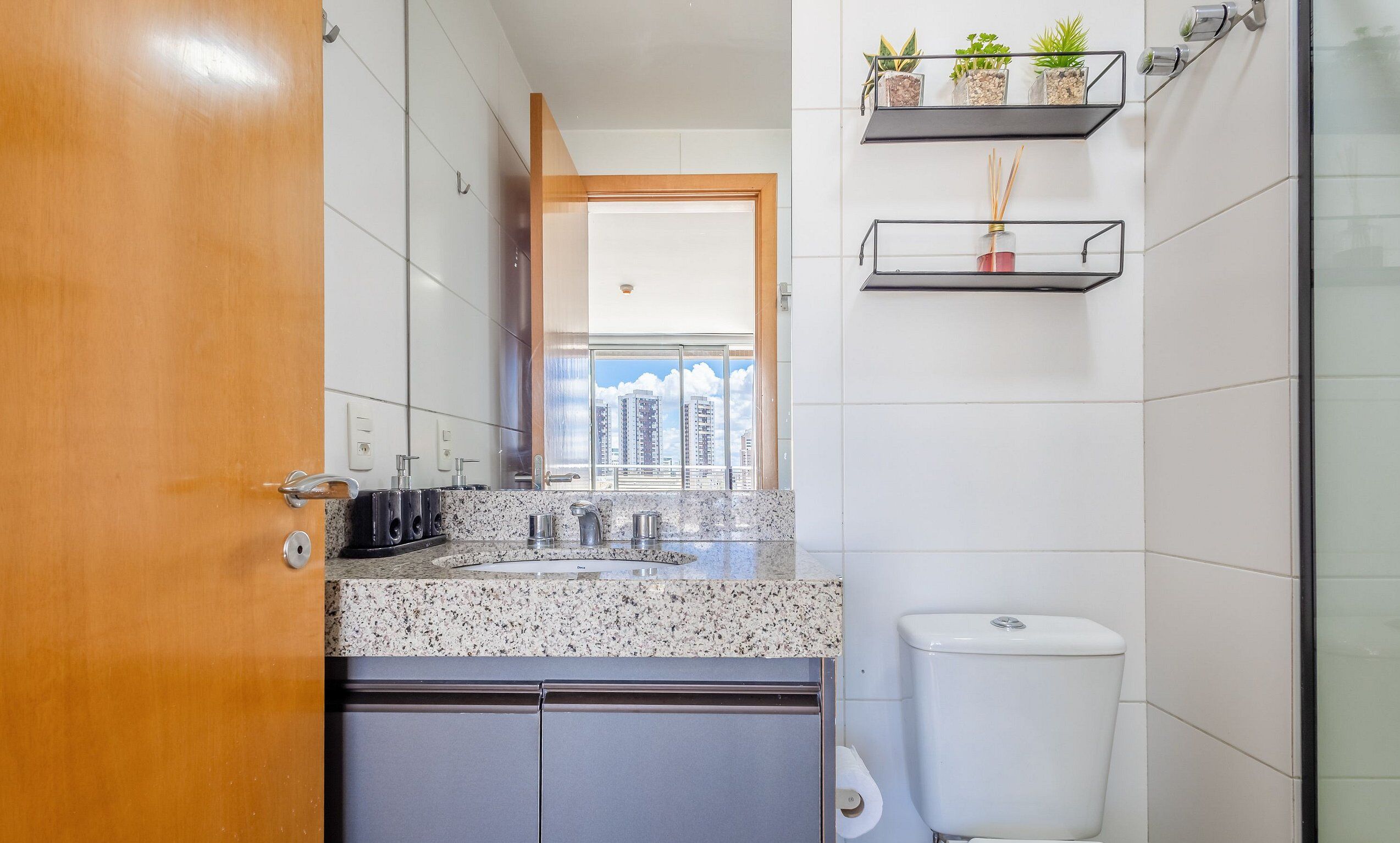 A modern bathroom with a granite countertop, a toilet, and a shower area.