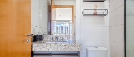 A modern bathroom with a granite countertop, a toilet, and a shower area.