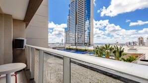 A balcony with a pool, a high-rise building in the background, and a clear sky. - Complete Stay and Pool in Aguas Claras - DPA (Águas Claras)