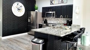A modern kitchen with black cabinets, stainless steel appliances, a marble island, and a black backsplash. - Pet friendly, upgraded townhouse, with heatable pool, and Jedi themed bedroom (Kissimmee)