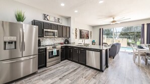 A modern kitchen with stainless steel appliances, a large island, and a view of a swimming pool. - Pet friendly, upgraded townhouse, with heatable pool, and Jedi themed bedroom (Kissimmee)