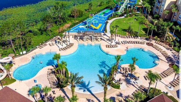 A large outdoor swimming pool with multiple lanes, surrounded by palm trees and lounge areas. - Pet friendly, upgraded townhouse, with heatable pool, and Jedi themed bedroom (Kissimmee)