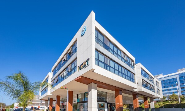 A modern hotel with a prominent '4' logo, multiple floors, and a covered entrance area. - Full Apartment in Setor Noroeste Eme0218 (Brasília)