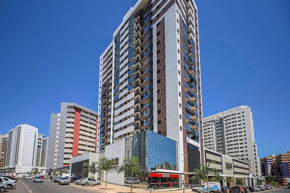 A high-rise building with multiple floors, a modern glass facade, and a commercial ground floor with a visible storefront. - Well-located apt in Aguas Claras Rmh1511 (Águas Claras)