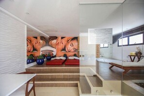 Area benessere con un'ampia murale, sedute rosse e un pannello in vetro.
