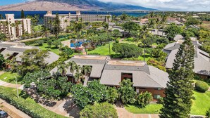 A resort with multiple buildings, a swimming pool, and a view of the ocean and mountains.