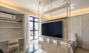 Un salon moderne avec un téléviseur à écran plat fixé au mur, une table basse en verre et des étagères intégrées.