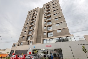 A multi-story building with a modern design, featuring a large entrance with a sign that reads "Essence." - EPK - Apartments in a Condo With Pool in Brasilia (Guará)