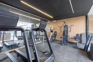 A modern gym with treadmills, elliptical machines, and weight stations. - EPK - Apartments in a Condo With Pool in Brasilia (Guará)