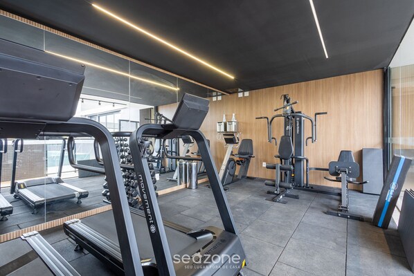 A modern gym with treadmills, elliptical machines, and weight stations.