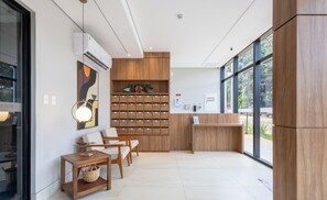 A modern reception area with a wooden reception desk, seating area, and a wall-mounted storage unit.