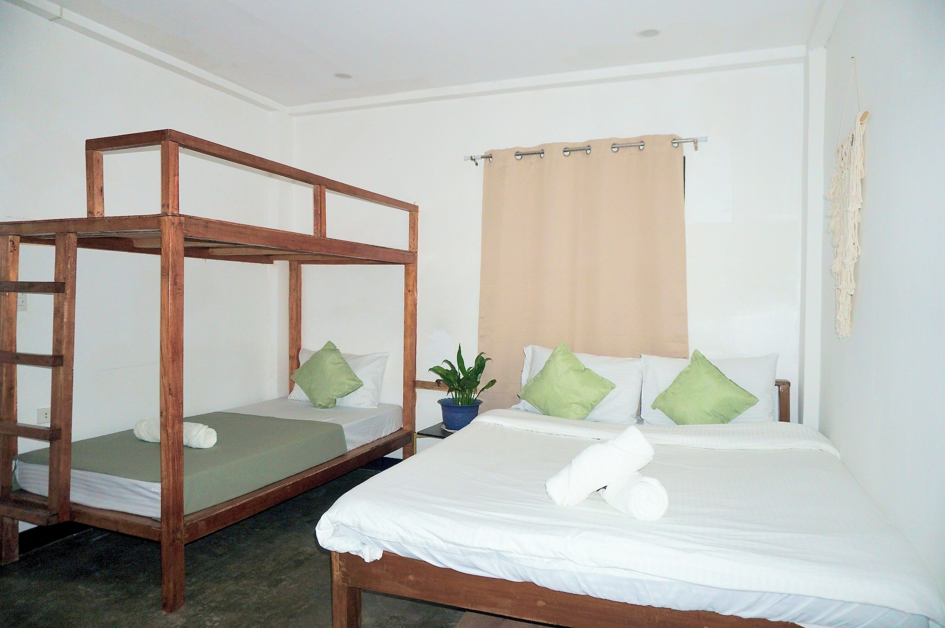 A room with two wooden bunk beds and a single bed with a beige curtain.