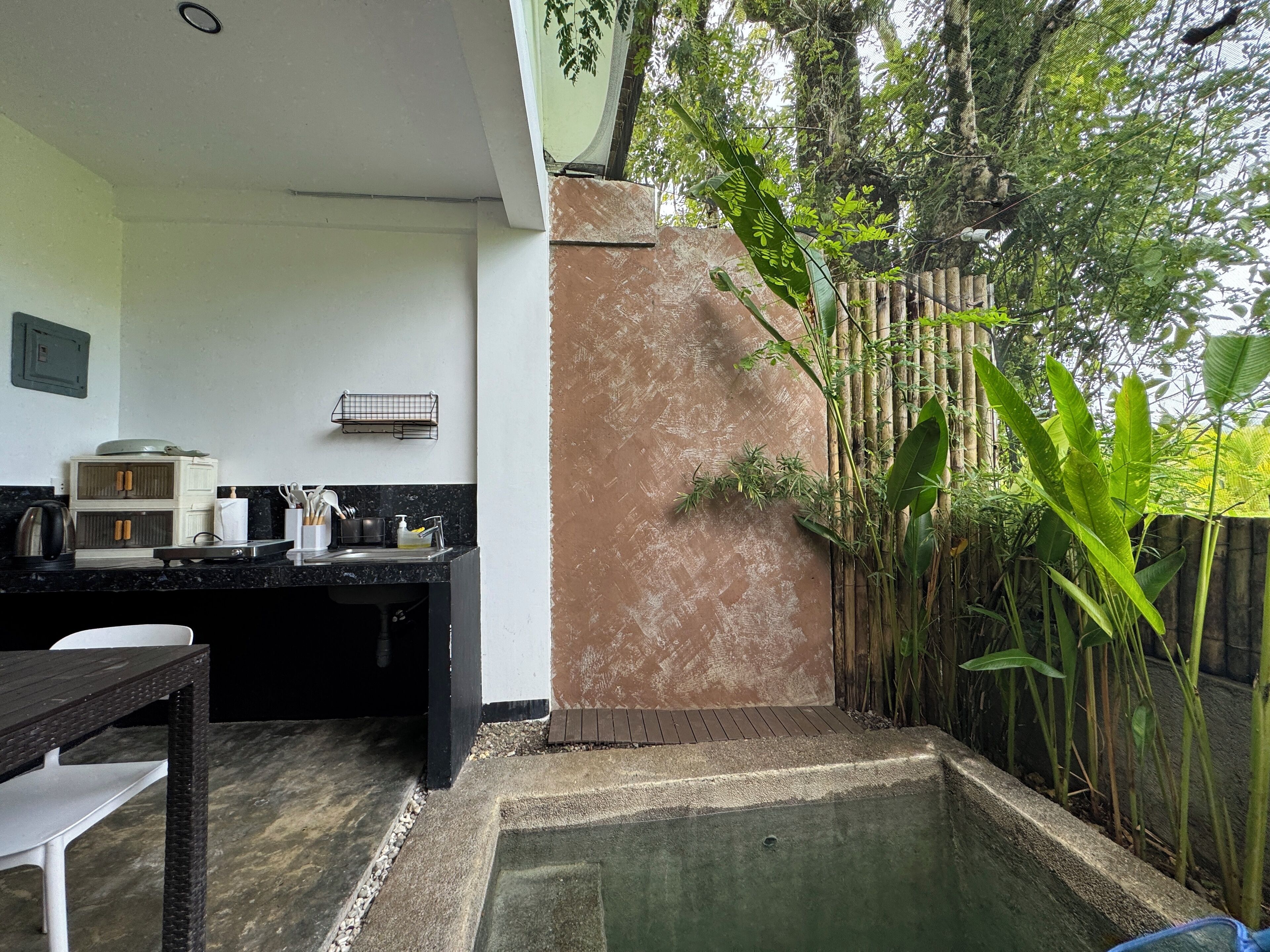 Cuina amb zona de menjador, una petita piscina i una tanca de bambú.