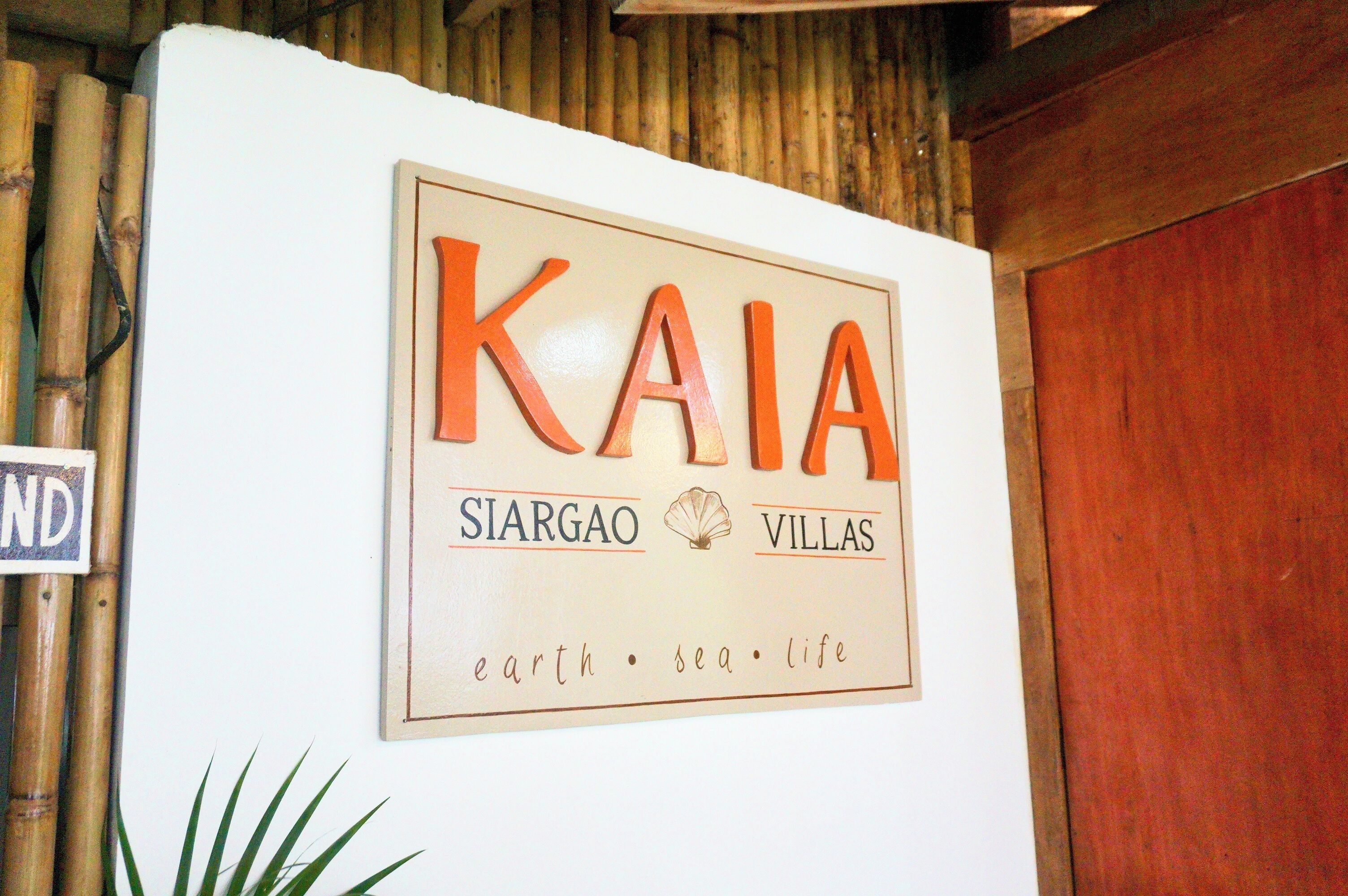 Een bord met 'KAIA SIARGAO VILLAS', met de slogan 'aarde • zee • leven'.