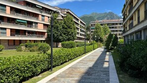 A multi-story hotel with balconies, a paved walkway, and lush greenery.