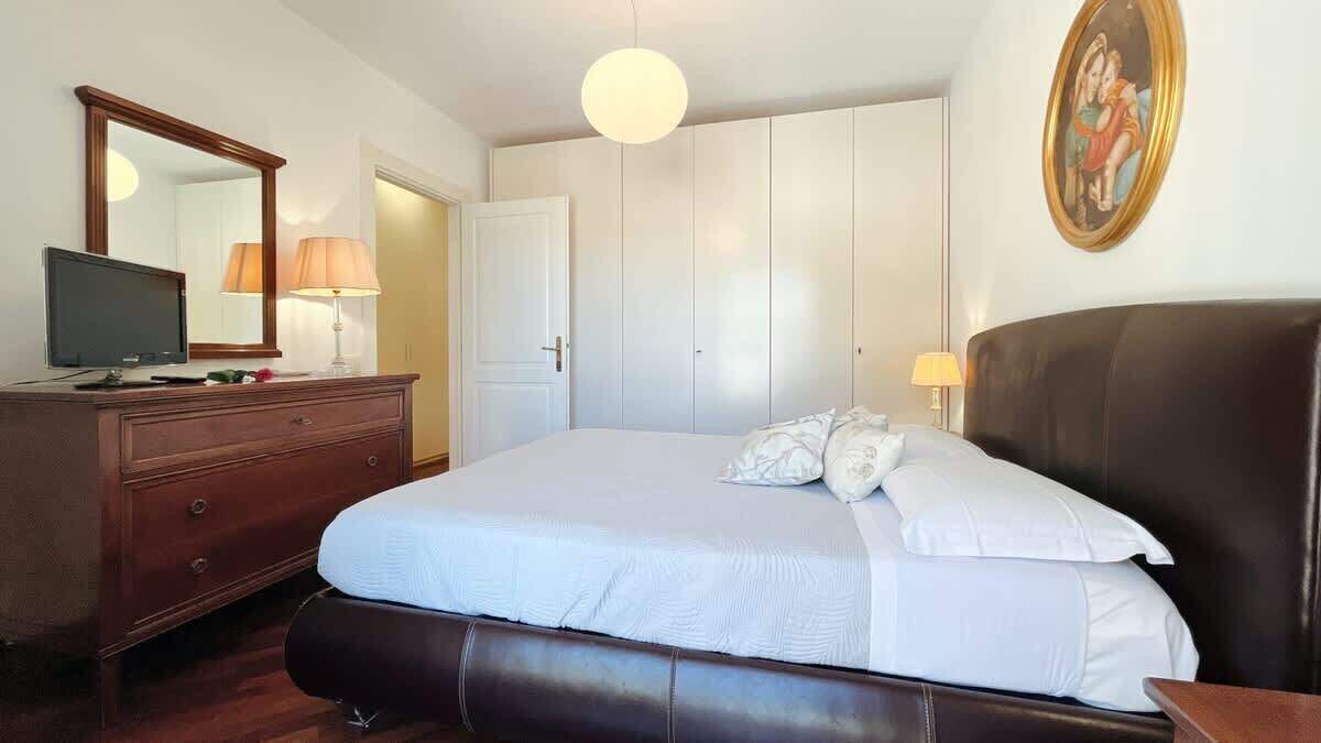 Un dormitorio con cama, cómoda, espejo y un cuadro en la pared.