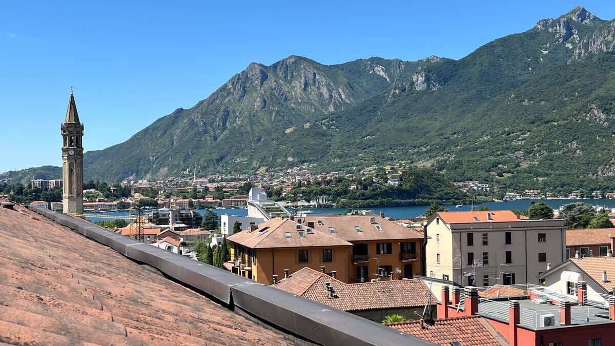 A coastal town with a prominent tower, terraced buildings, and a mountainous backdrop.