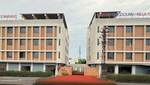 A modern hotel with a flat facade, multiple floors, and a central entrance with a red flower bed. - Hotel Blue Ocean (Udaipur)