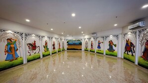 A spacious hall with a polished marble floor and walls adorned with traditional murals. - Hotel Blue Ocean (Udaipur)