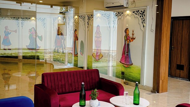 A hotel lobby with red and blue seating, decorative glass panels, and a ceiling with pink lighting. - Hotel Blue Ocean (Udaipur)