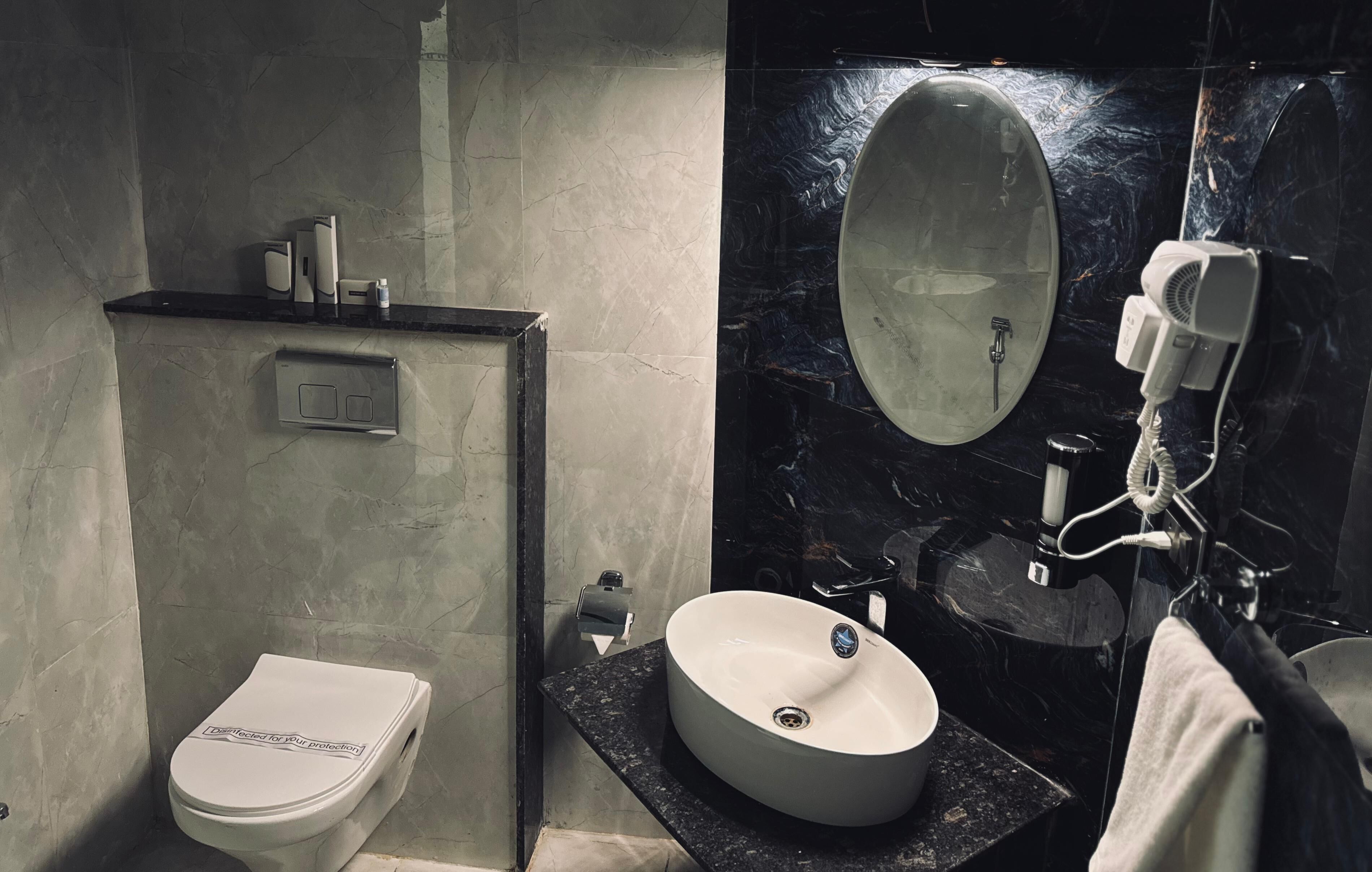 A modern bathroom with a toilet, sink, and mirror.