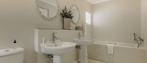 A bathroom with two sinks, a toilet, and a bathtub.