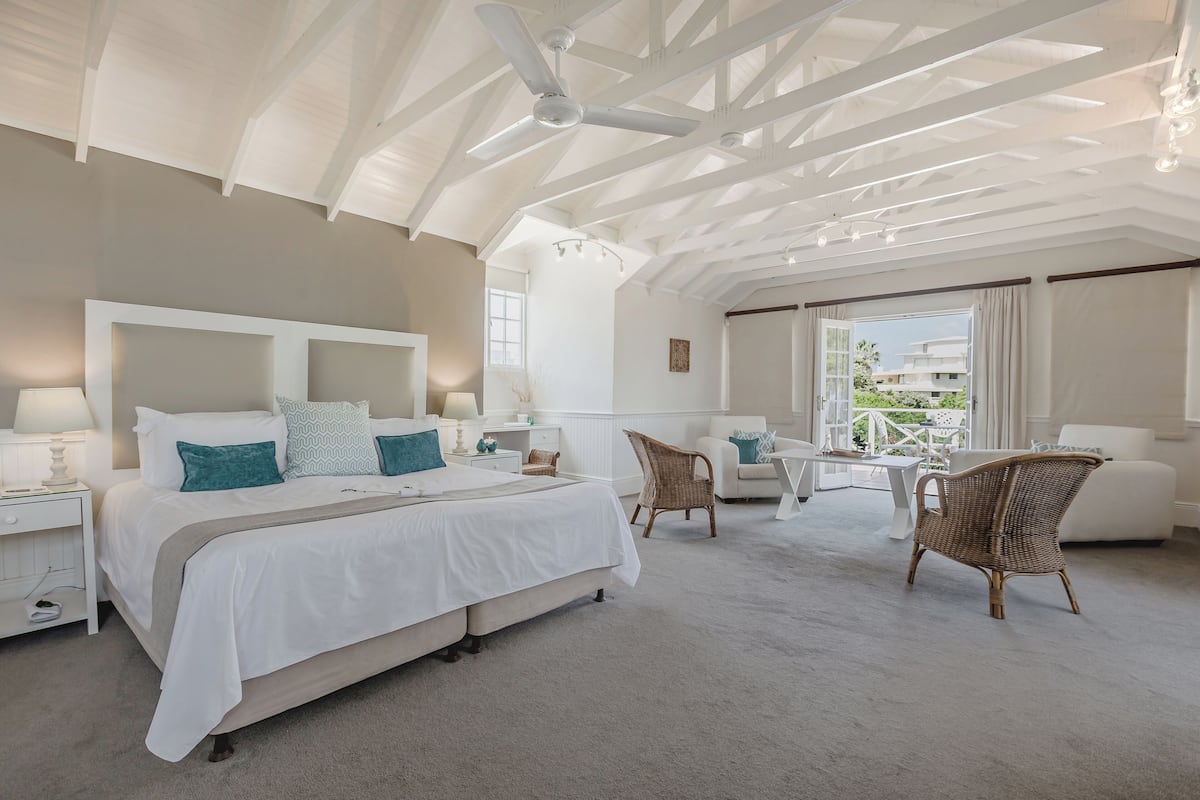 A spacious bedroom with a large bed, a ceiling fan, and a view of the outdoors.