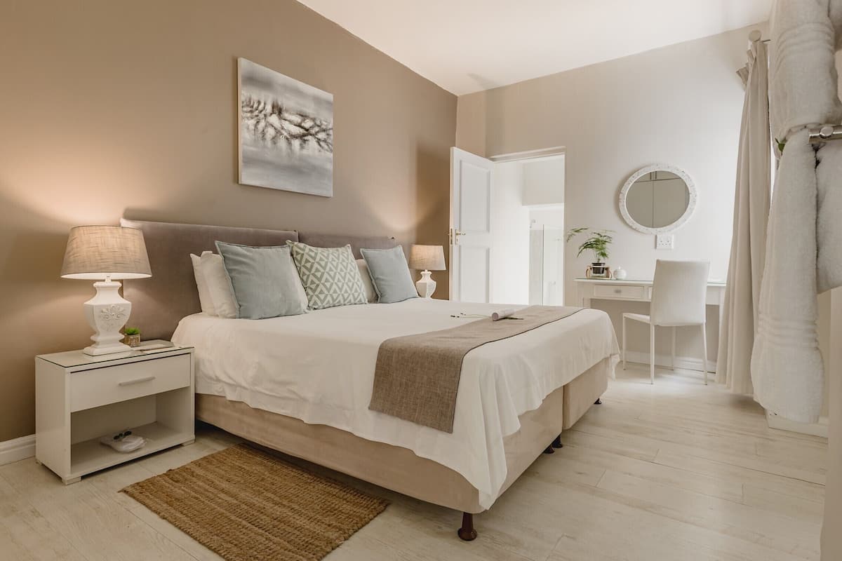 A bedroom with a bed, nightstand, desk, chair, and a mirror.
