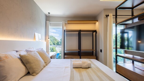 Habitación de hotel moderna con una cama grande, vestidor y televisión.