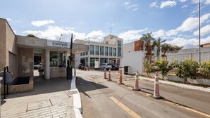 Un edificio con un cartel que dice "Condomínio do Edifício Central Park" y un estacionamiento con coches y una motocicleta.