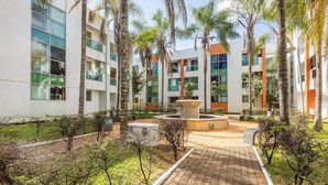Un edificio moderno de varios pisos, con amplios ventanales y un patio central con una fuente.