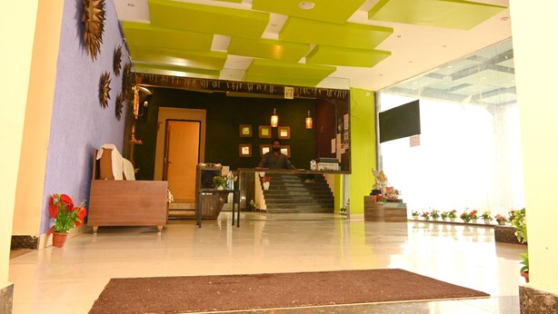 A hotel lobby with a reception desk, a staircase, and a large window. - Hotel Ryaan Inn  (Raipur)