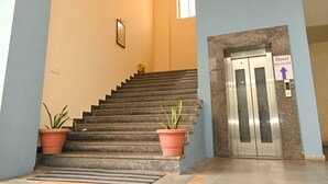 A hotel entrance with a staircase, potted plants, and an elevator. - Hotel Ryaan Inn  (Raipur)