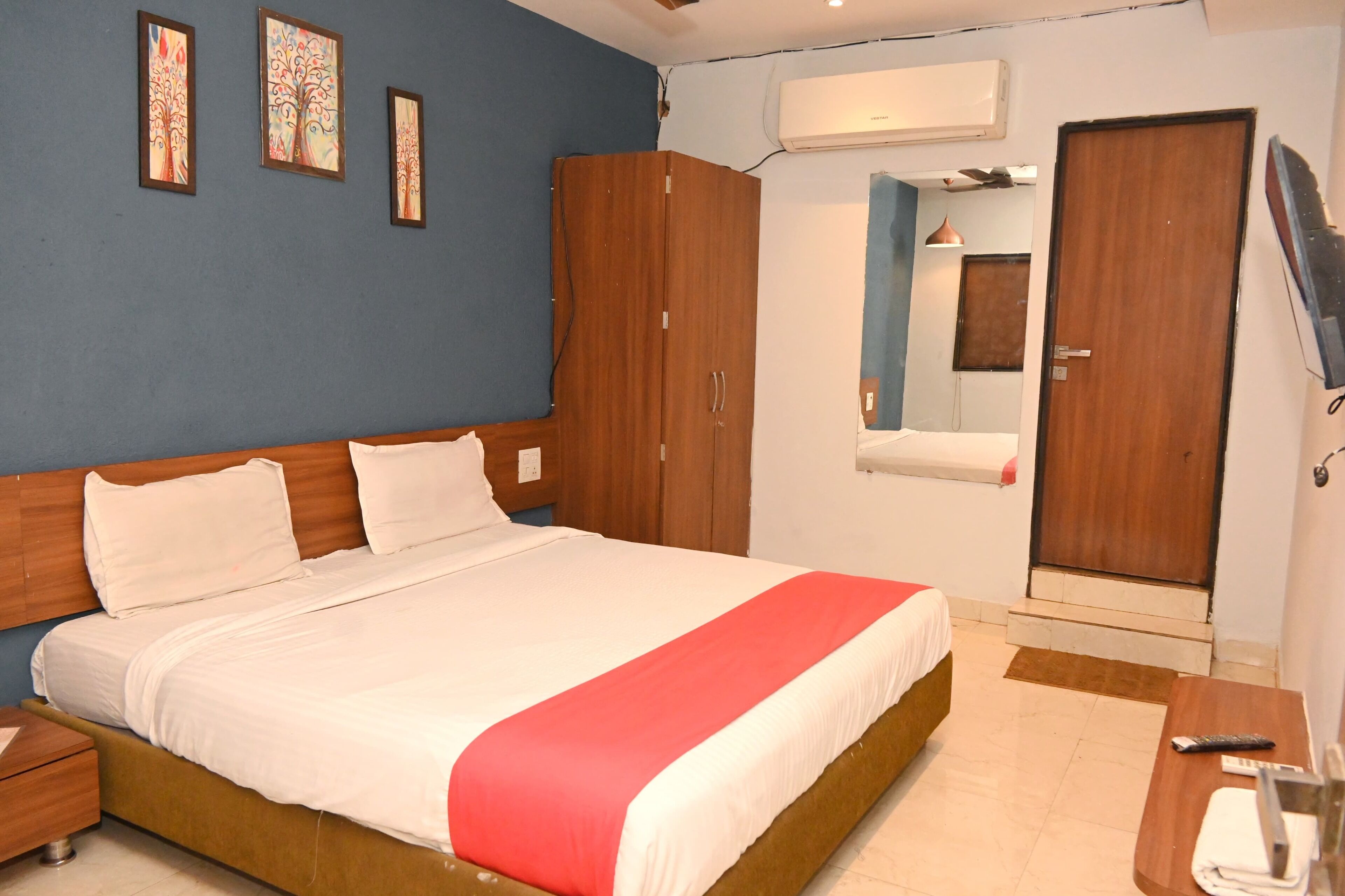 A hotel room with a large bed, wooden wardrobe, and a TV.