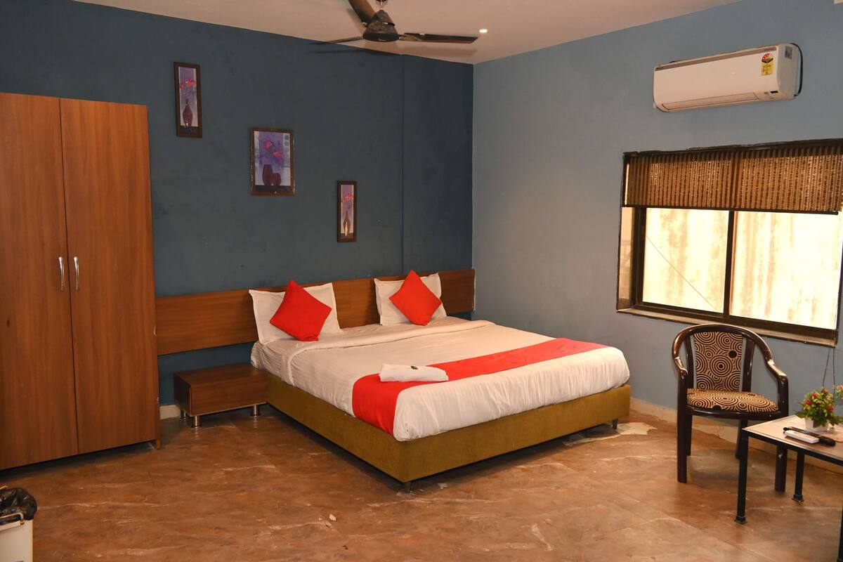 Un dormitorio con una cama, un armario de madera, una silla, una mesita y una ventana con persianas.