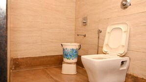 A bathroom with a toilet and bidet, tiled walls, and a showerhead. - Hotel Ryaan Inn  (Raipur)