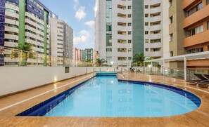 A swimming pool with a blue tiled edge, surrounded by a low brick wall and a glass railing. - Luxury Penthouse w/ Jacuzzi in Brasilia Bcy2001 (Águas Claras)