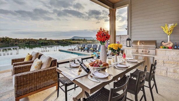 An outdoor dining area with a view of a lake, a grill, and a pool. - Sunset Oaks Estate I: Waterfront, Infinity Pool, Hot Tub & Game Room! (Kingsland)