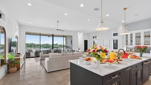 A modern kitchen with a large island, dark cabinetry, and a view of the outdoors. - Sunset Oaks Estate I: Waterfront, Infinity Pool, Hot Tub & Game Room! (Kingsland)