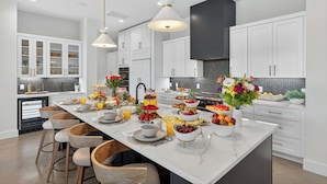 A modern kitchen with white cabinetry, a marble island, and pendant lighting. - Sunset Oaks Estate I: Waterfront, Infinity Pool, Hot Tub & Game Room! (Kingsland)