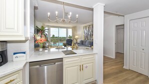 A modern kitchen with white cabinetry, a stainless steel dishwasher, and a chandelier.