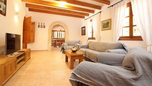 A cozy living room with a wooden TV stand, a sofa, and a dining area in the background. - LES PALMERES (LLEIDA). Quite and peaceful (Pollensa)