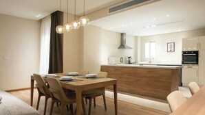A modern kitchen with a central island, wooden dining table, and chairs. - Kennah Milena | Akoya Residence, New Cairo (New Cairo)
