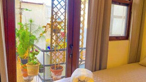 A room with a bed, a window, and potted plants.