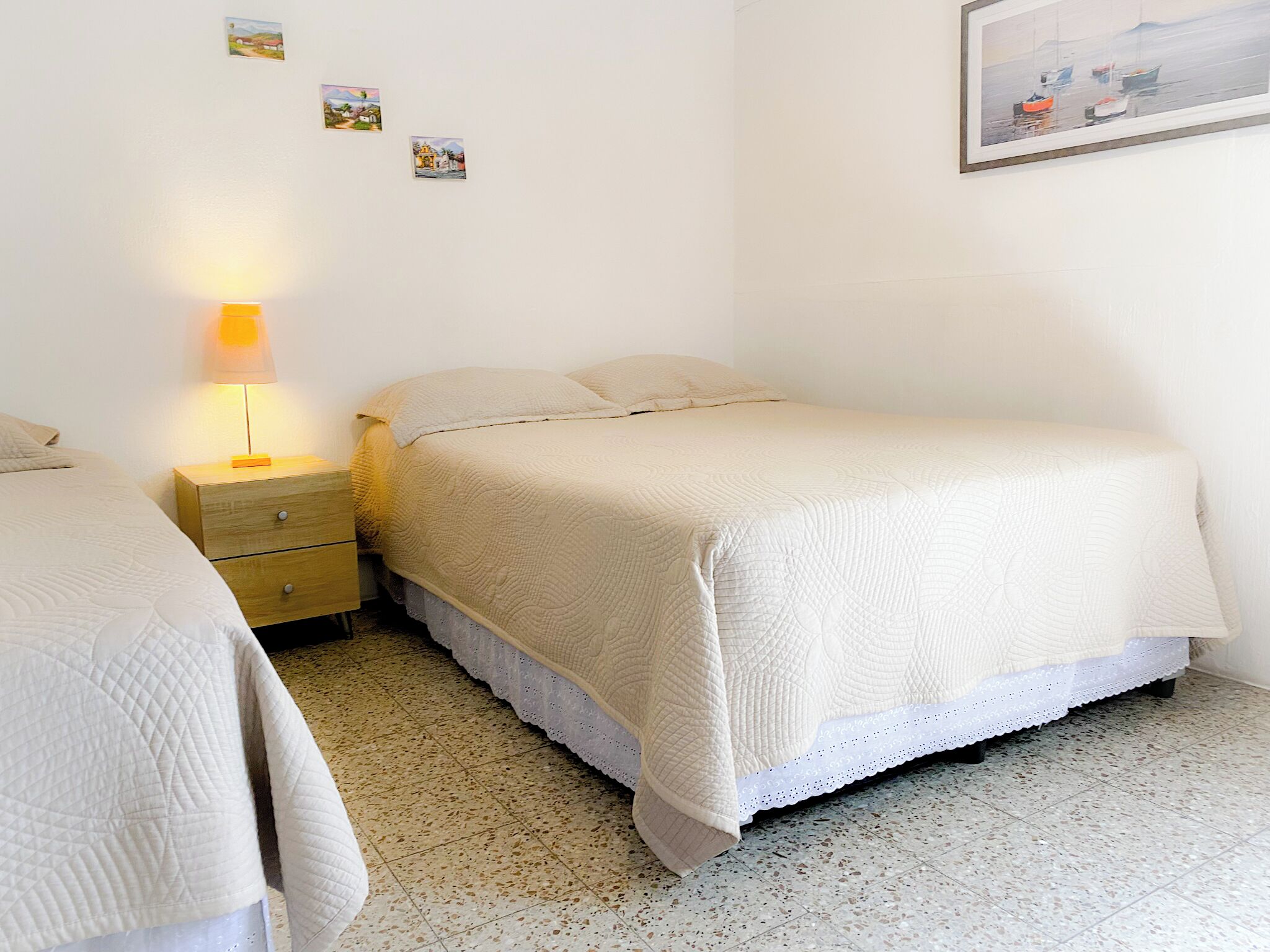 A bedroom with a bed, a nightstand, a lamp, and a small wall-mounted picture.