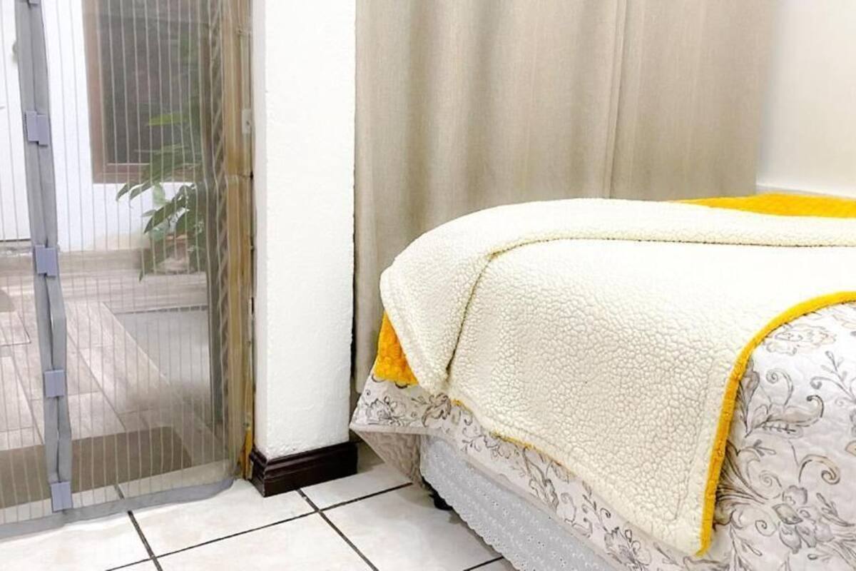 Een slaapkamer met een bed, een schuifglasdeur en uitzicht op het omliggende landschap.