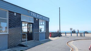 Un bâtiment portant l’inscription « The Boat House », avec une vue dégagée sur la mer en arrière-plan.